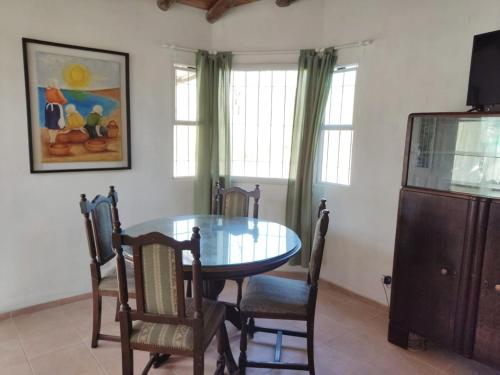 Un comedor con una mesa de cristal y sillas. en Cabana Cecilia, en Villa Icho Cruz