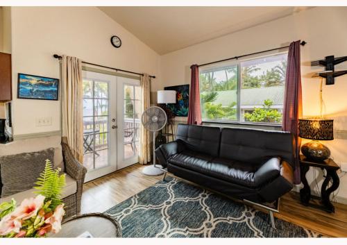 a living room with a black leather couch and a window at The Dolphin Cottage at Kehena Beach in Kehena