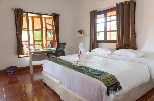 a bedroom with a bed and a desk and windows at Samma Karuna Beach & Wellness Resort - Intoxicants free in Haad Chao Phao