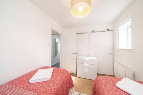 a white bedroom with two beds and a window at At The Bay in St. Andrews