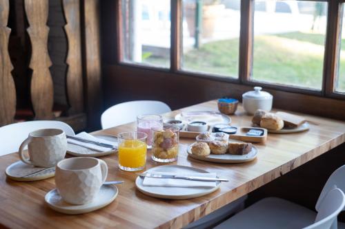 a wooden table topped with cups and plates of breakfast food at POSADA NEHUEN in Villa General Belgrano