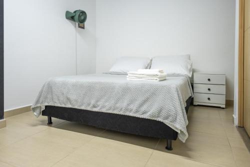 a white bedroom with a bed and a night stand at Coliving Tonchalá Laureles Habitaciones y Apartamentos Familiares con Cocina cerca del Estadio in Medellín