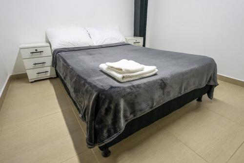 a bed with two white towels on top of it at Coliving Tonchalá Laureles Habitaciones y Apartamentos Familiares con Cocina cerca del Estadio in Medellín