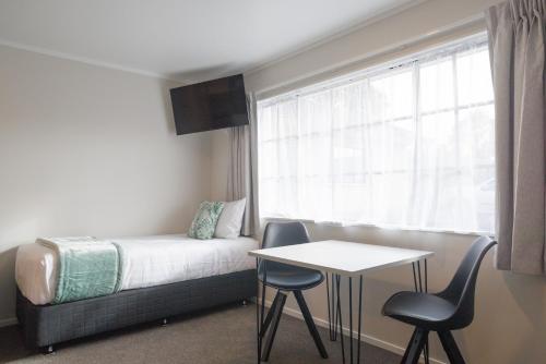 a bedroom with a bed and a table and a window at BK's Pohutukawa Lodge in Whangarei