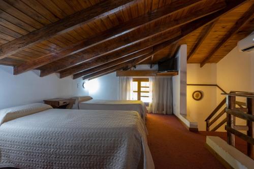 a bedroom with two beds in a room with wooden ceilings at POSADA NEHUEN in Villa General Belgrano