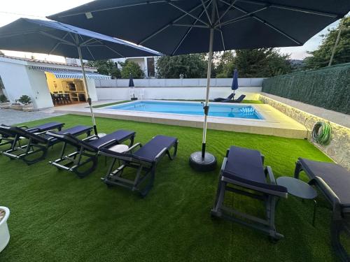 a group of chairs and an umbrella next to a pool at Alojamento Rio Neiva in Tregosa