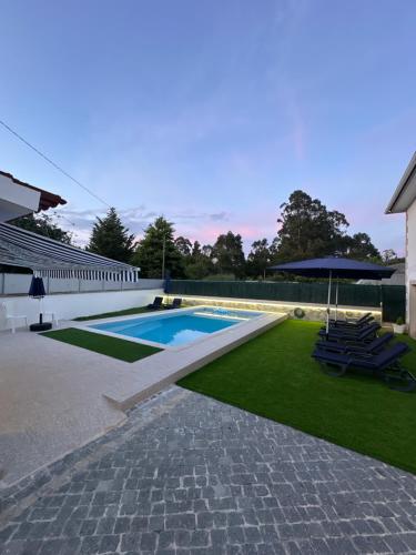 a swimming pool with two lawn chairs and an umbrella at Alojamento Rio Neiva in Boticas