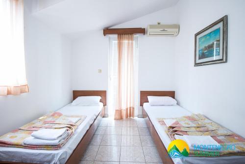 two beds sitting in a room with a window at Apartments Becici in Budva