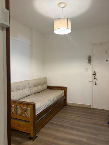 a bed in a room with a white wall at Departamento frente al casino in Mar del Plata