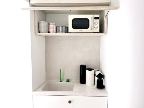 une cuisine avec un micro-ondes et un évier dans l'établissement Design & cool appartement, à Paris