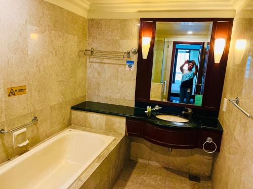a person taking a picture of a bathroom with a tub and sink at Marmaid Suite At Time Square KL in Kuala Lumpur