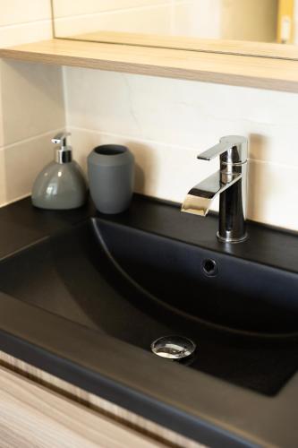 a black bathroom sink with a chrome faucet at Appartement des 5 Trésors - piscine et vue panoramique in Case-Pilote