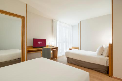 a hotel room with two beds and a mirror at Exe Area Central in Santiago de Compostela