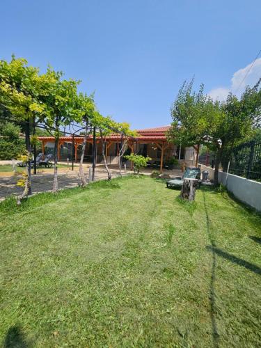 a yard with grass and trees in front of a building at Villa Pelagie Bliss in Nea Kalikratia