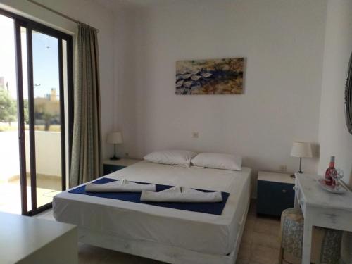 a bedroom with a bed and a large window at Hotel Narkissos in Archangelos