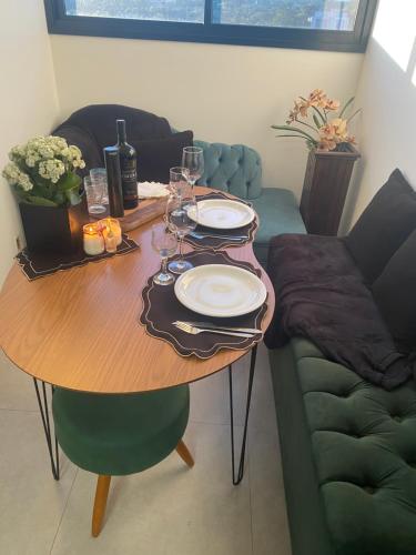 a wooden table with wine glasses and a couch at Suíte com Charme, Conforto e Vista das Montanhas in Jaguariúna
