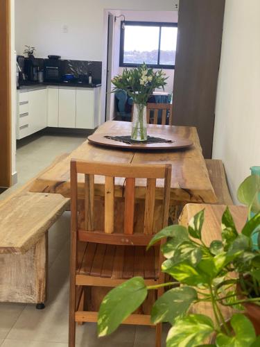 a wooden table with a vase of flowers on it at Suíte com Charme, Conforto e Vista das Montanhas in Jaguariúna