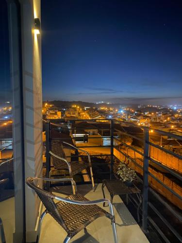 two chairs sitting on top of a balcony at night at Suíte com Charme, Conforto e Vista das Montanhas in Jaguariúna