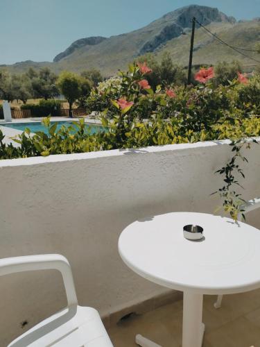 a white table and a white chair and a table and flowers at Hotel Narkissos in Archangelos