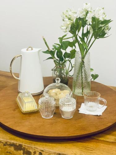 a wooden table with a tray with cups and vases at Suíte com Charme, Conforto e Vista das Montanhas in Jaguariúna