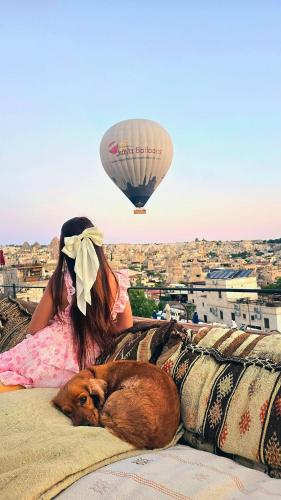 a girl and a dog laying on a couch with a hot air balloon at Onur Cave Cappadocia in Goreme