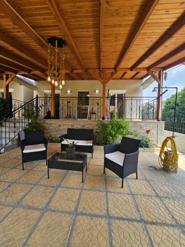 a patio with chairs and tables and a wooden ceiling at Villa Pelagie Bliss in Nea Kalikratia