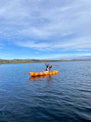 a person in an orange kayak in the water at Uros Titicaca Beluxia in Puno