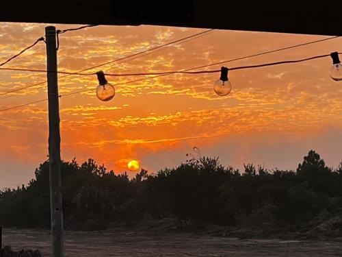 a sunset with lights hanging from a wire at Rincon de los Michis in Barra del Chuy