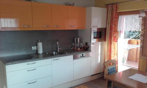 a kitchen with white cabinets and a sink and a table at Haus Sagl in Nauders