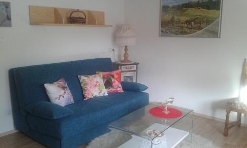 a living room with a blue couch and a glass table at Haus Sagl in Nauders