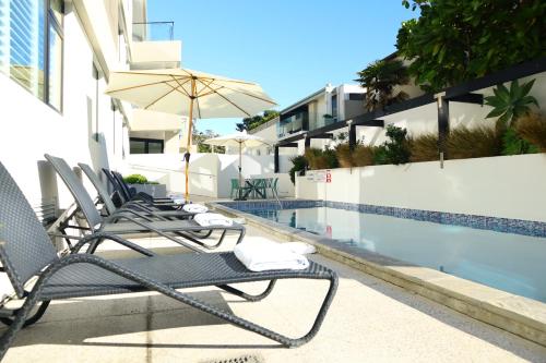 a row of lounge chairs next to a swimming pool at Belle Mer Beachfront Apartments in Mount Maunganui