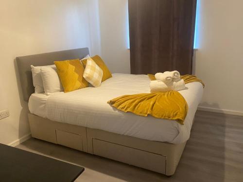 a bed with yellow pillows and a teddy bear on it at Stylish spacious 2 bed Apt Balcony Nr City Stadium in Manchester