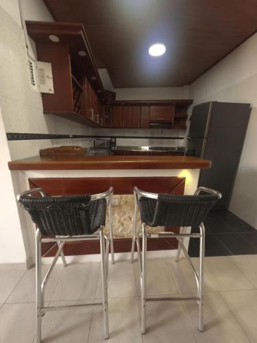 a kitchen with two chairs in front of a counter at Glamar suits in Arboletes