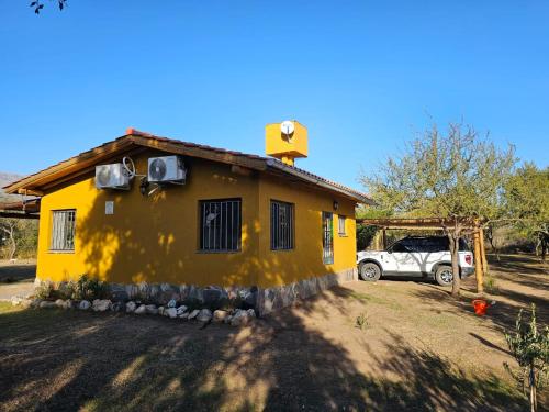 a yellow house with a car parked in front of it at Arawi Cabaña in Merlo