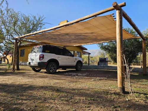 a white suv parked under a wooden structure at Arawi Cabaña in Merlo