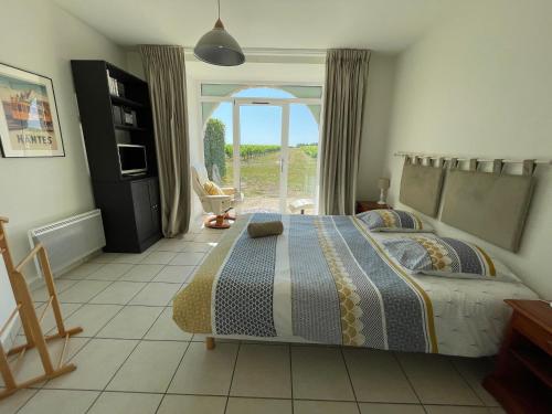 une chambre avec un lit et une grande fenêtre dans l'établissement Gîte confortable au cœur des vignes avec terrasse, vélos, WiFi et équipements bébé à 17 km de Nantes - FR-1-306-808, à Châteauthébaud