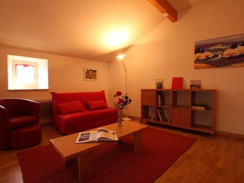 a living room with a red couch and a table at Maison pittoresque avec terrasse et BBQ, calme près de Langeac - FR-1-582-124 in Langeac