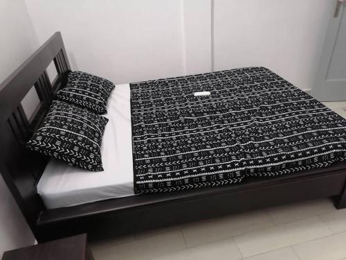 a black and white bed with two pillows on it at La Résidence Reine in Cotonou