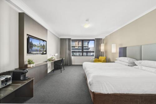 a hotel room with a large bed and a desk at Bright Studio with Pool Access in Parramatta in Sydney