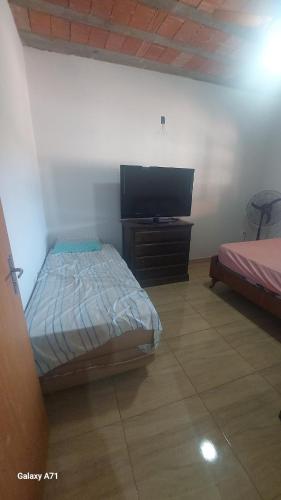 a bedroom with a bed and a flat screen tv at Chácara Stella in Ribeirão Preto