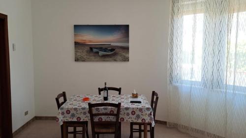 a dining room with a table with chairs and a picture at La Villetta sul mare in Marina di Modica