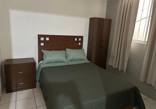 a bedroom with a bed with a green bedspread and a wooden headboard at Casa Michel in Tepic
