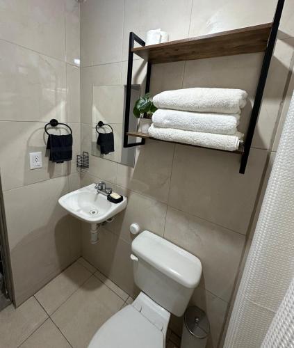 a bathroom with a toilet and a sink and towels at Casa Michel in Tepic