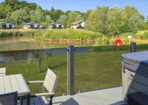 a deck with a table and chairs next to a body of water at Serenity Lakes in Fleet