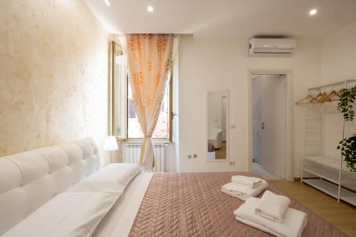 a white bedroom with a large white bed with two towels at San Pietro Roma Suite in Rome
