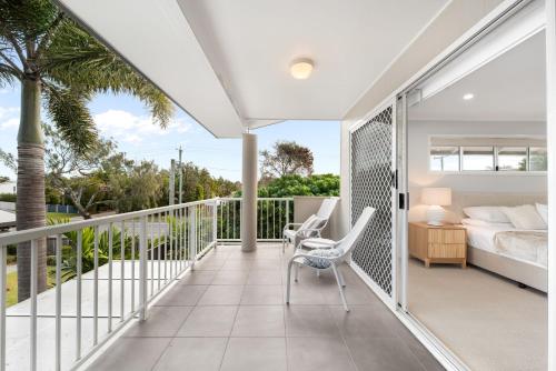 a room with a balcony with a bed and a bed and chair at Unit 4 Tuscany Shores in Marcoola