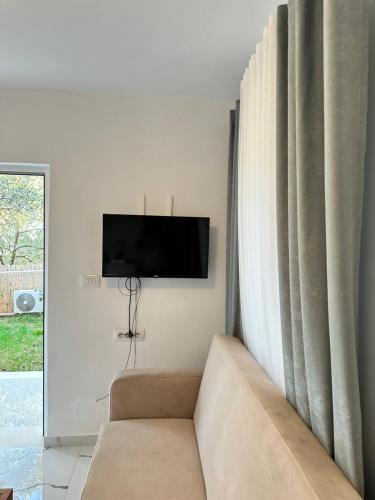 a living room with a couch and a tv on a wall at Vila 44 in Sarandë