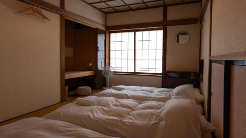 a large bed in a room with a window at Hakuba Hospitality Inn YUKINOSO in Hakuba