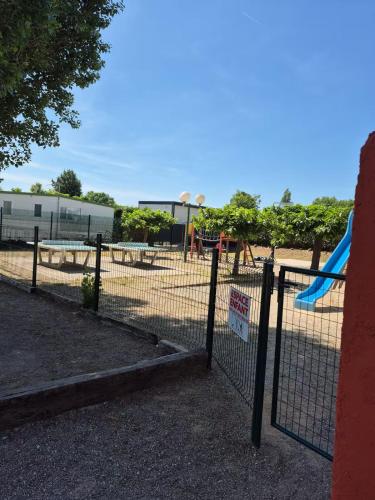 a fence in front of a playground with a slide at Mobil-Home Le Provençal in Fréjus
