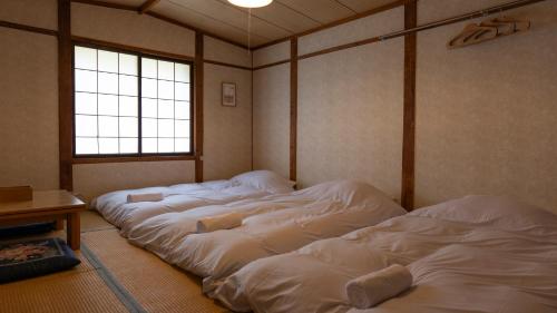a room with three large white beds in it at Hakuba Hospitality Inn YUKINOSO in Hakuba